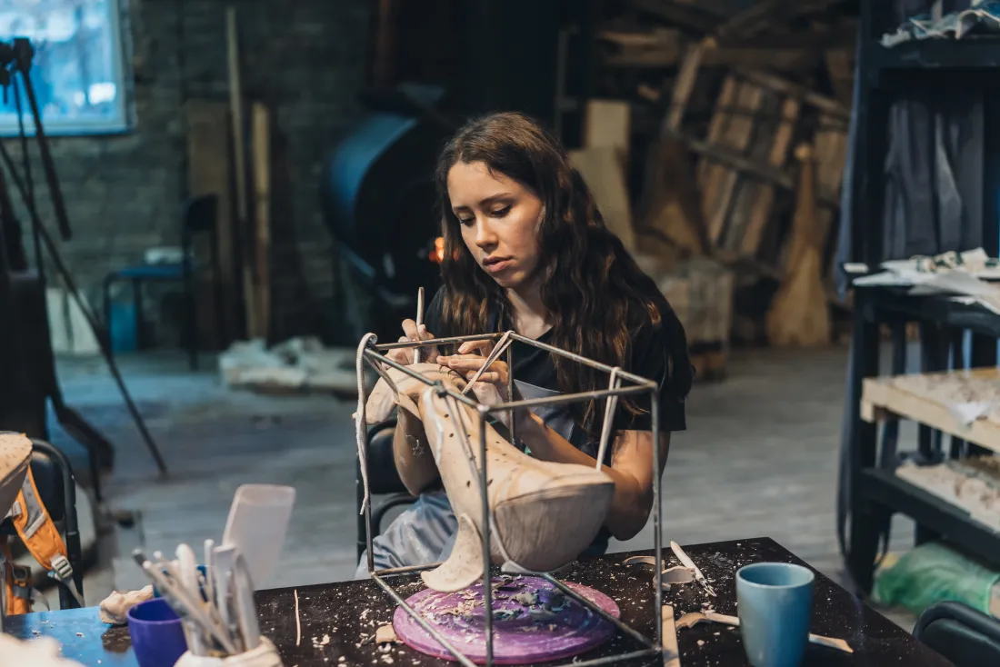 Bachelor of Fine Arts student sculpting a clay artwork in the Raga studio